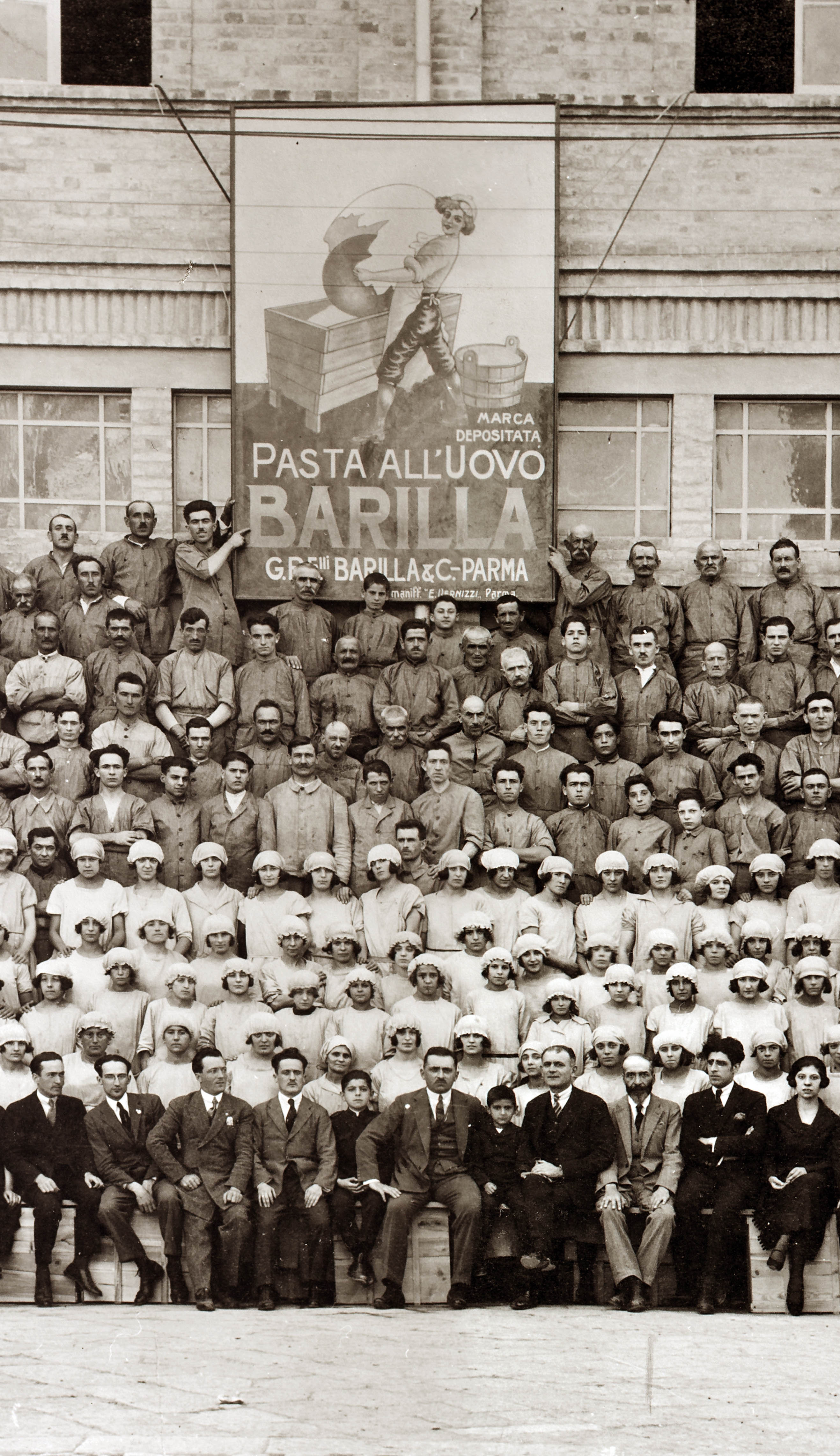 Luigi Vaghi, foto maestranze Barilla, 1923. Al centro Riccardo Barilla con i figli Pietro e Gianni e, alla sinistra del piccolo Gianni, il Procuratore del pastificio, Gualtiero Medioli (Parma, Archivio Storico Barilla).